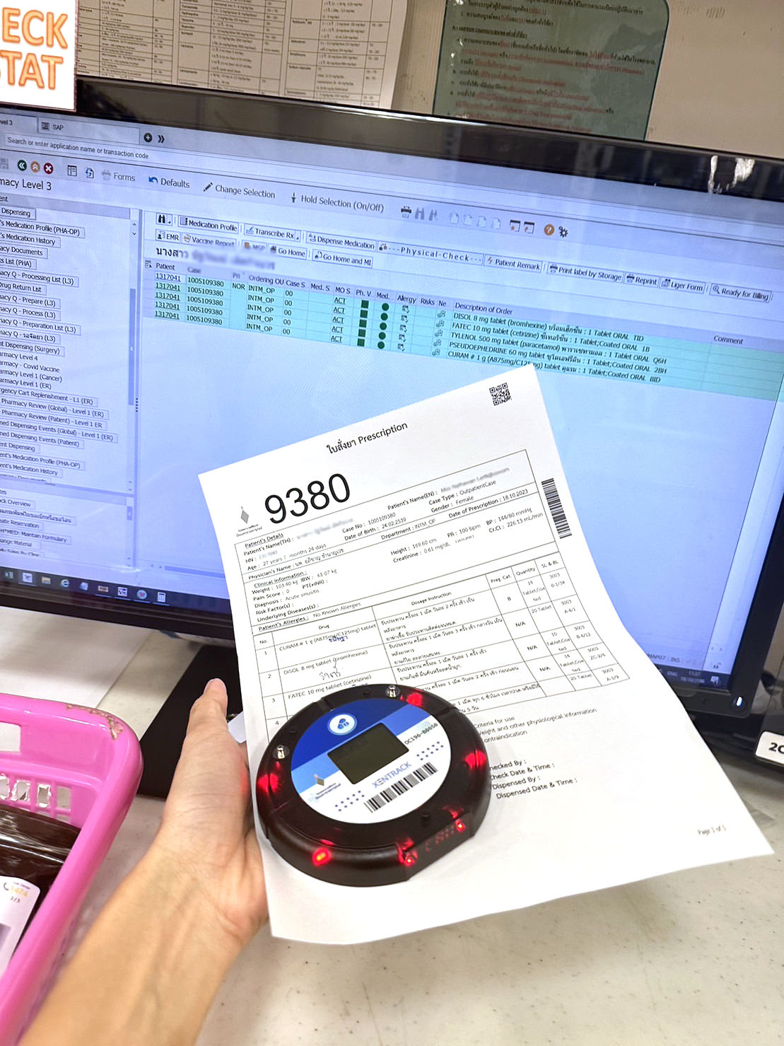 A prescription form with Beeper 9380 displayed in front of a hospital pharmacy system screen. | ใบสั่งยาพร้อมบี๊บเปอร์หมายเลข 9380 แสดงอยู่หน้าจอระบบห้องยาโรงพยาบาล