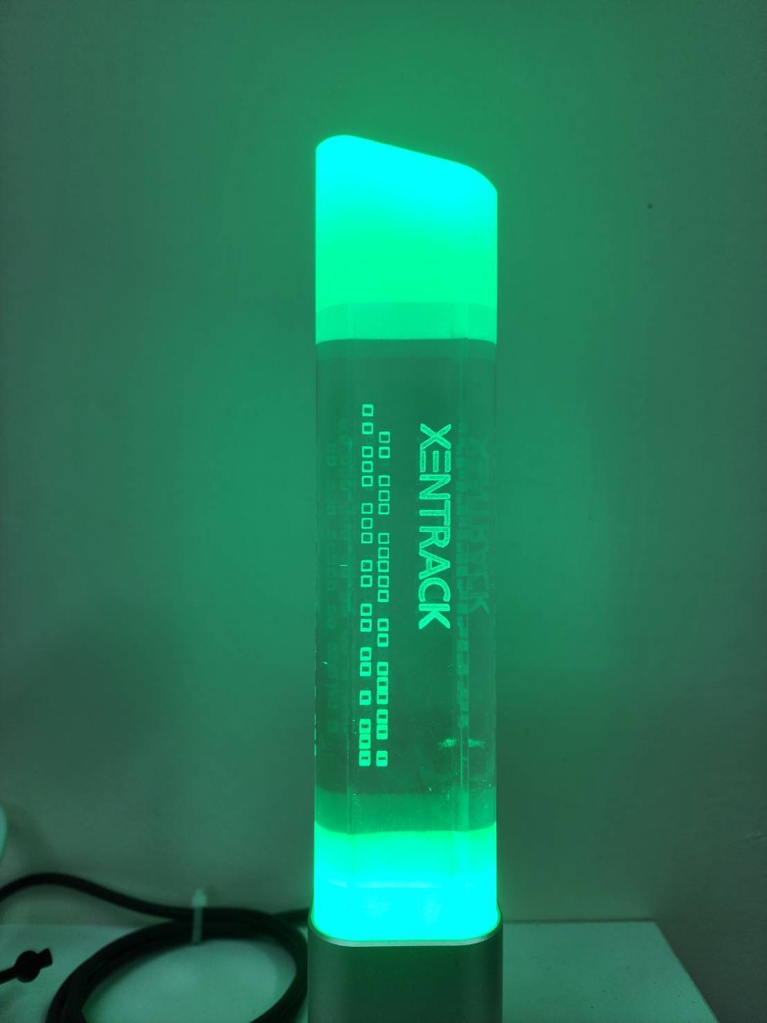 HAPYbot Alert Pole glowing green with "XENTRACK" branding. | เสาแจ้งเตือน HAPYbot เรืองแสงสีเขียว พร้อมโลโก้ "XENTRACK"