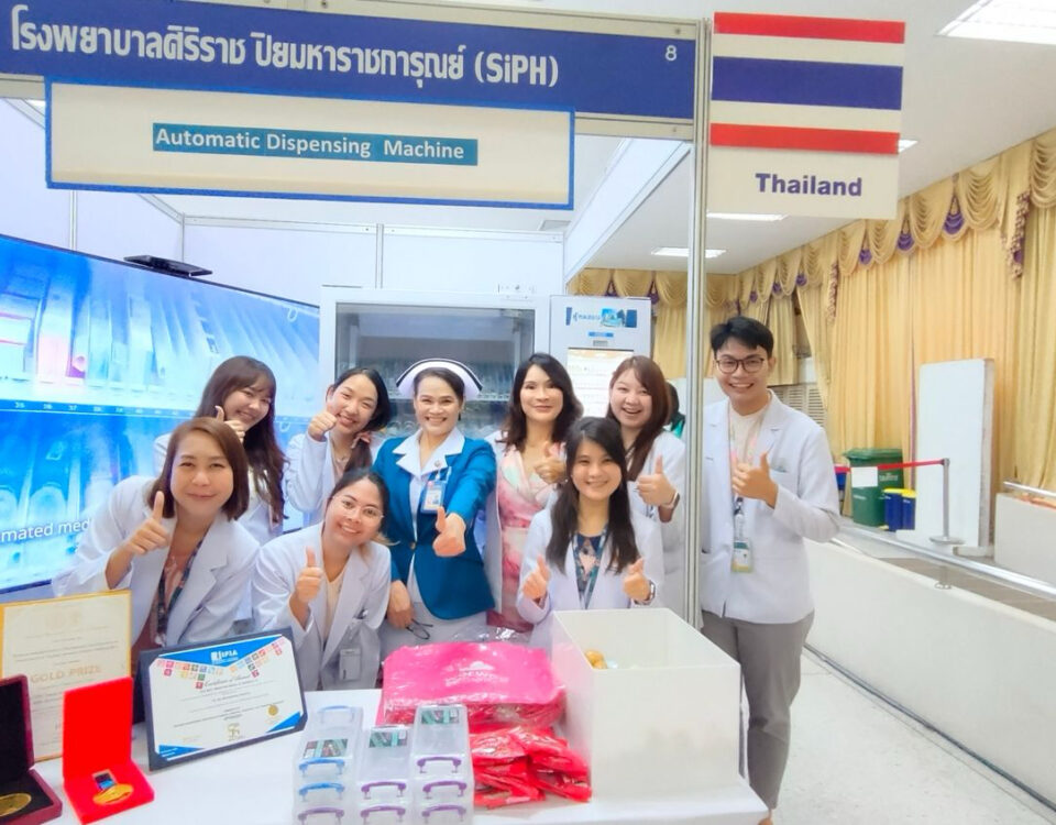 Medical professionals from Siriraj Piyamaharajgarun Hospital posing with an automatic dispensing machine at a healthcare exhibition in Thailand