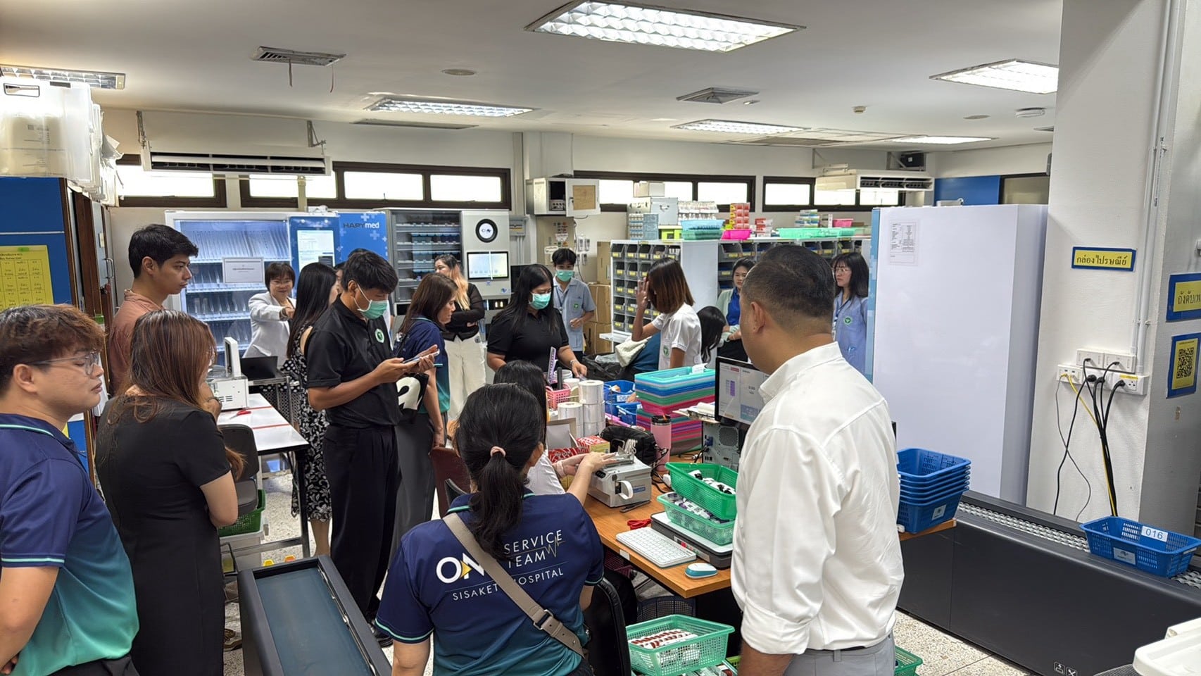 คณะจากโรงพยาบาลศรีสะเกษ สวมเสื้อ ONE SERVICE TEAM เยี่ยมชมห้องยาผู้ป่วยนอกที่ติดตั้งระบบจัดยาอัตโนมัติ HAPYmed ณ รพร.สระแก้ว